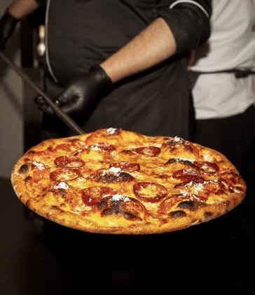 A KRISP chef carrying a freshly baked pizza from the oven